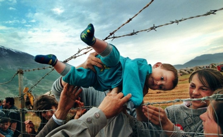 Agim-Shala-passed-through-barbed-wire-fence-to-his-family-at-Kosovo-refugee-camp