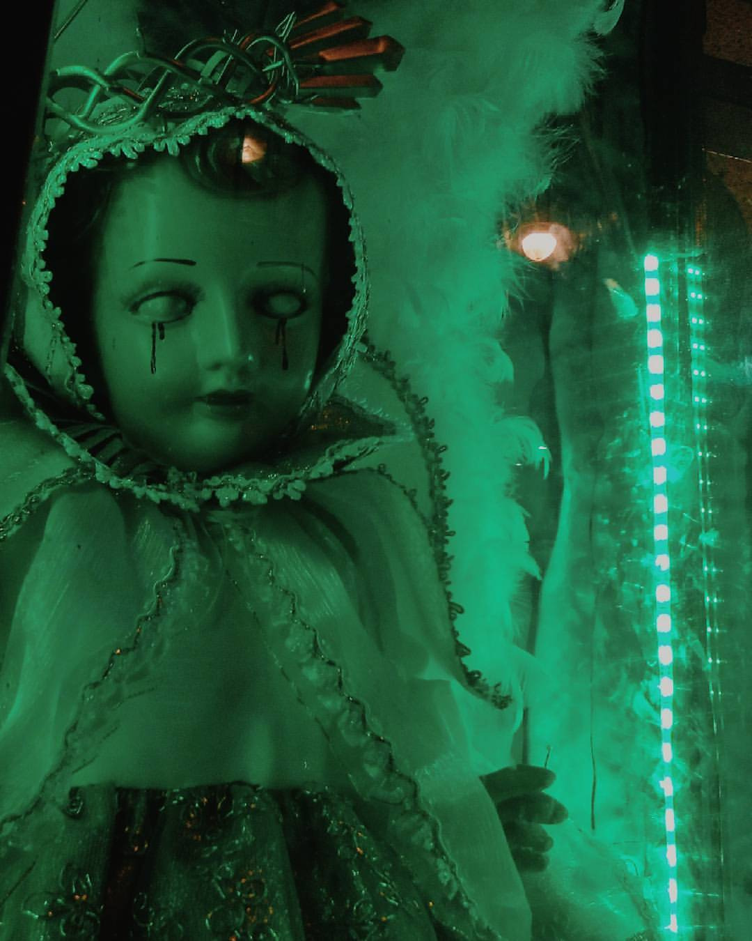 dark image of a doll dressed in christening clothes with blood tears